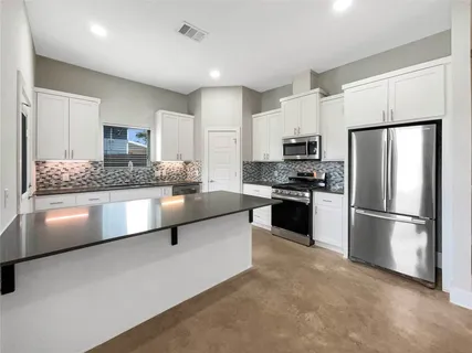 a kitchen with granite countertop white cabinets and stainless steel appliances