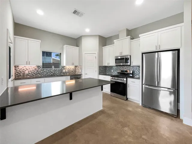 a kitchen with granite countertop white cabinets and stainless steel appliances