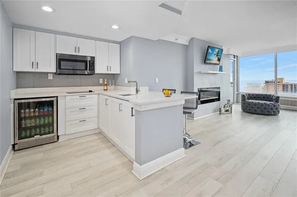 a view of kitchen with stainless steel appliances granite countertop a stove top oven a sink dishwasher and a refrigerator with wooden floor