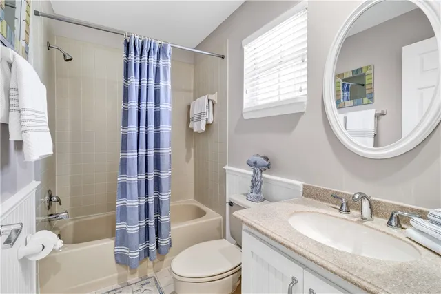 a bathroom with a granite countertop toilet a sink a mirror a bathtub and shower