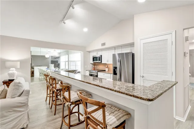 a large kitchen with kitchen island a large counter top space and stainless steel appliances