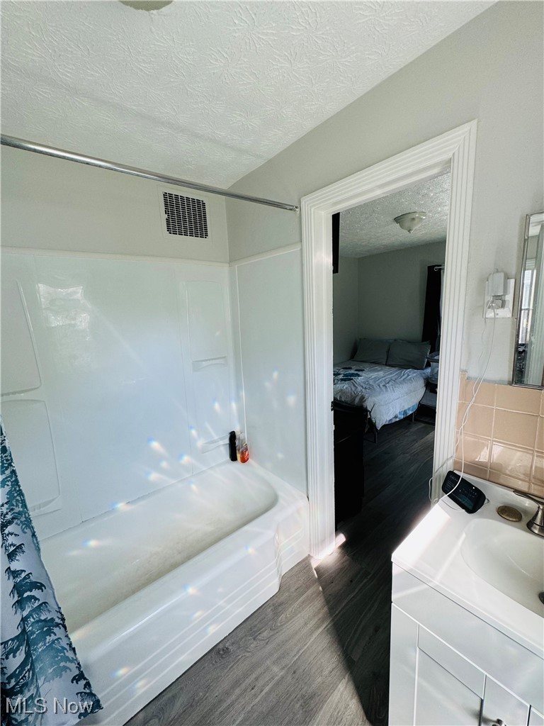 930 Reed Avenue Akron, OH 44306 - Photo 15 of 23 Bathroom featuring a textured ceiling, wood-type flooring, vanity, and shower / bathtub combination with curtain