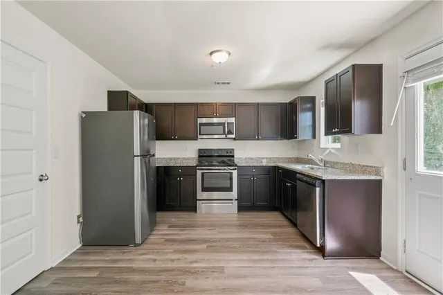 a kitchen with granite countertop a refrigerator and a stove top oven