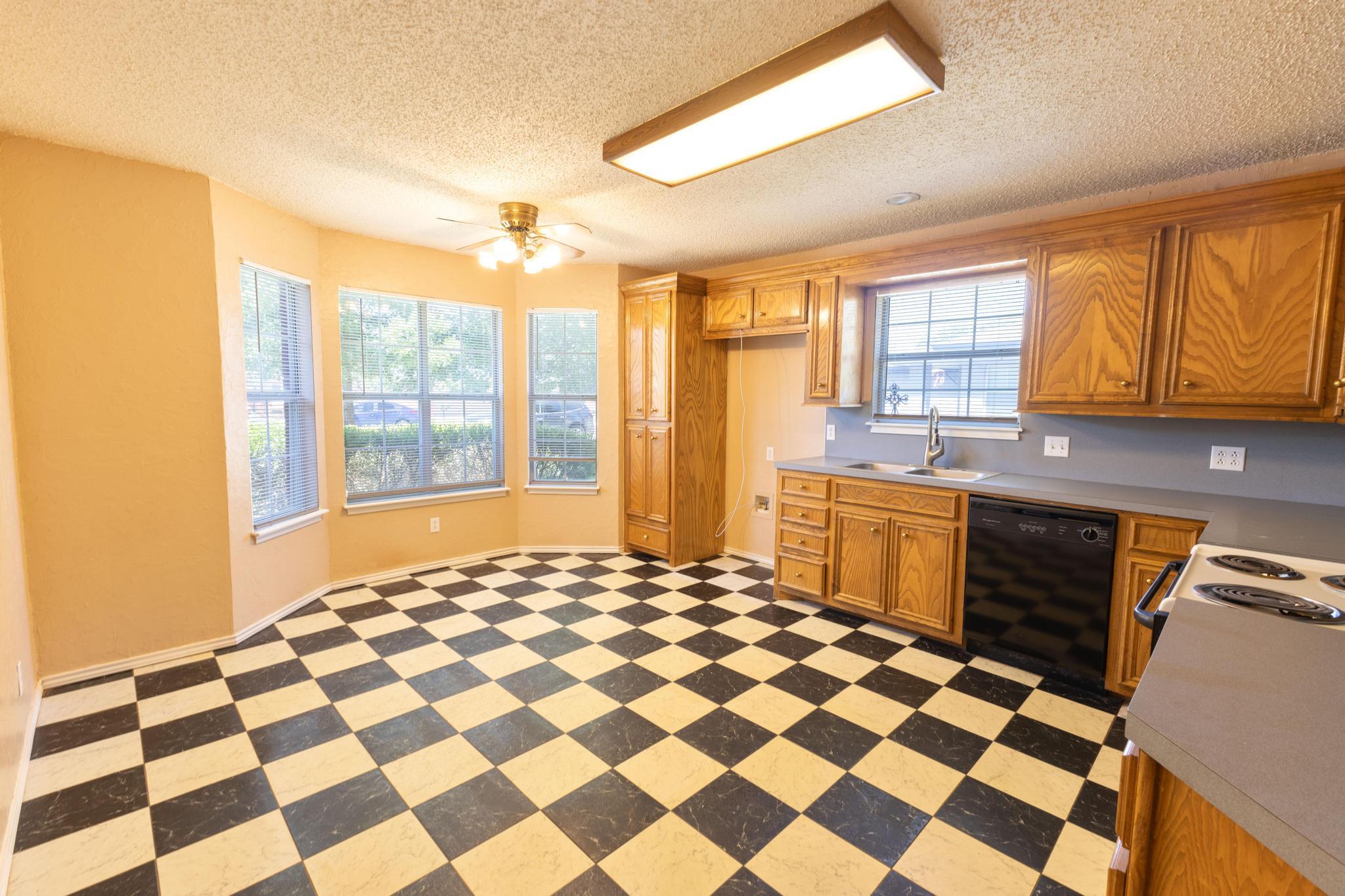 6115 8th Street Lubbock, TX 79416 - Photo 2 of 18 a kitchen with a checkered floor and a window