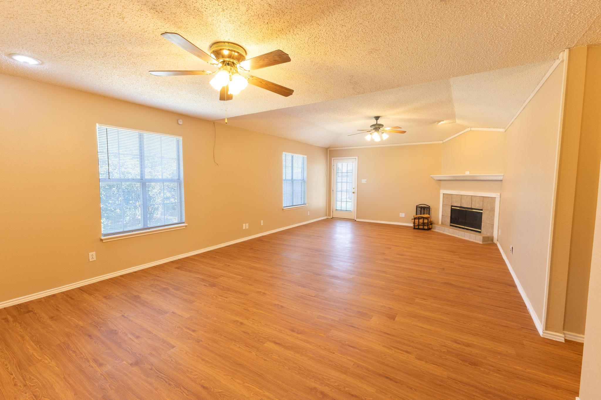 6115 8th Street Lubbock, TX 79416 - Photo 6 of 18 a view of an empty room with a window and wooden floor