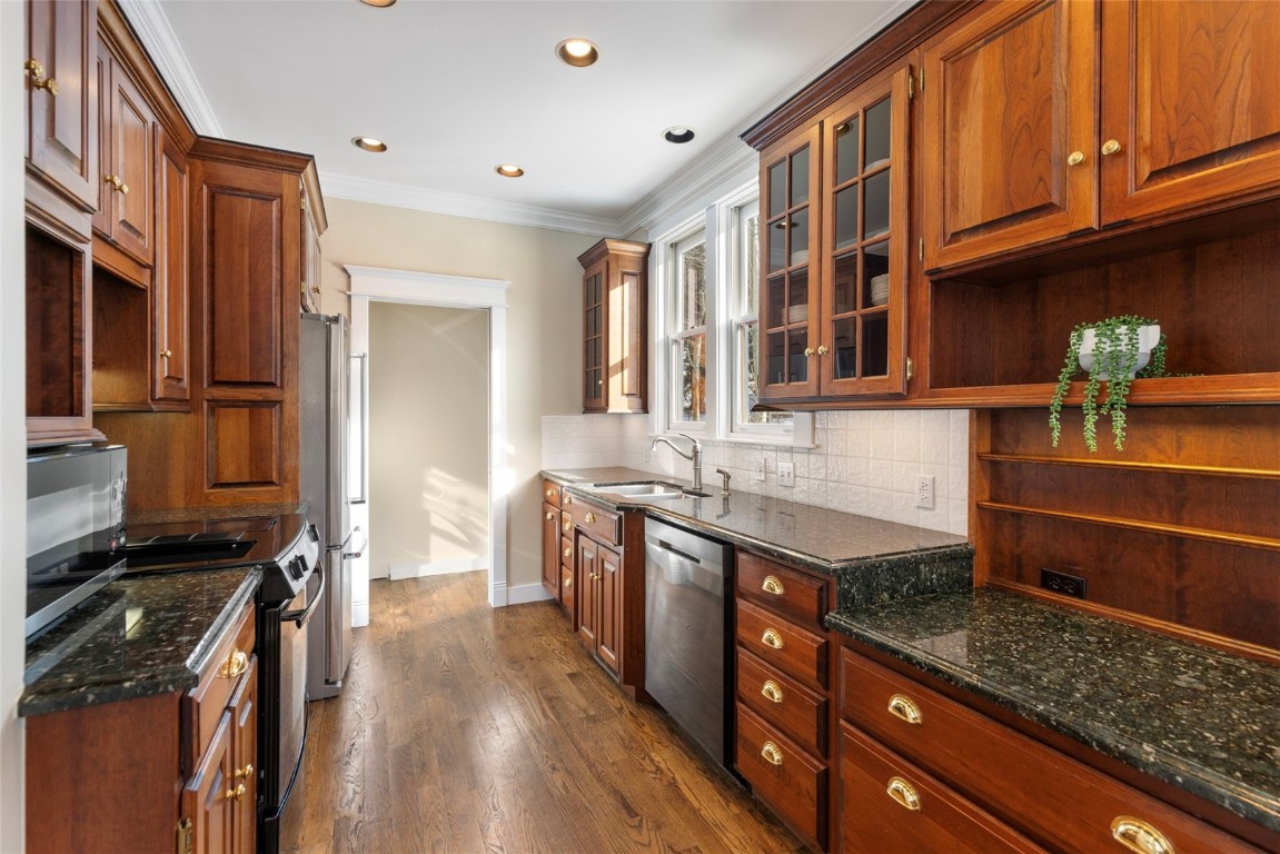 192 Wellington Road Breckenridge, CO 80424 - Photo 13 of 50 Kitchen with stainless steel appliances, dark stone counters, glass insert cabinets, ornamental molding, and dark wood-style floors