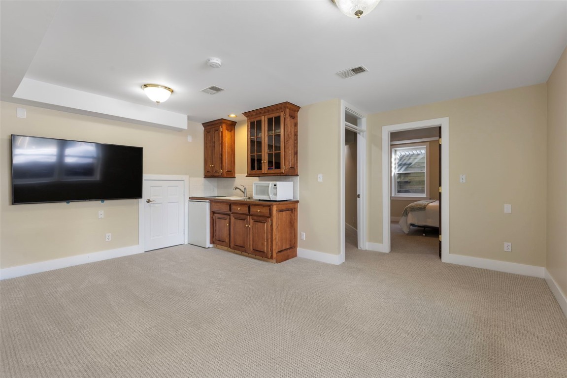192 Wellington Road Breckenridge, CO 80424 - Photo 35 of 50 Bar area featuring brown cabinets, glass insert cabinets, white microwave, and light carpet