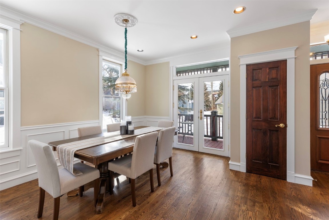 192 Wellington Road Breckenridge, CO 80424 - Photo 8 of 50 Dining space featuring a chandelier, ornamental molding, wainscoting, dark wood-style flooring, and a decorative wall