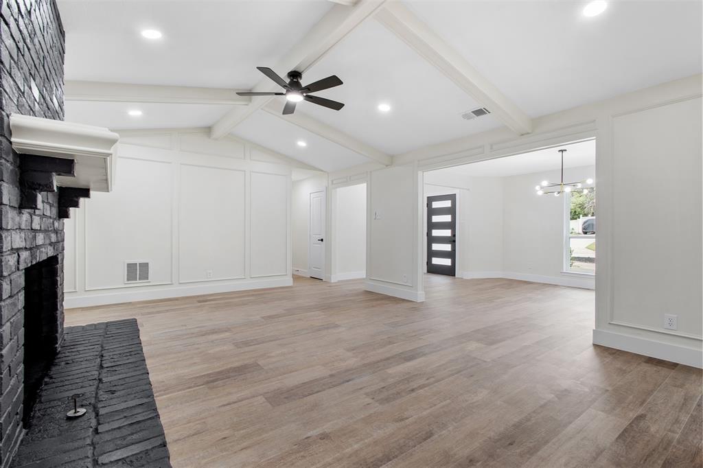 2816 Quail Ridge Drive Carrollton, TX 75006 - Photo 3 of 33 Unfurnished living room featuring a fireplace, light wood finished floors, ceiling fan, and a chandelier