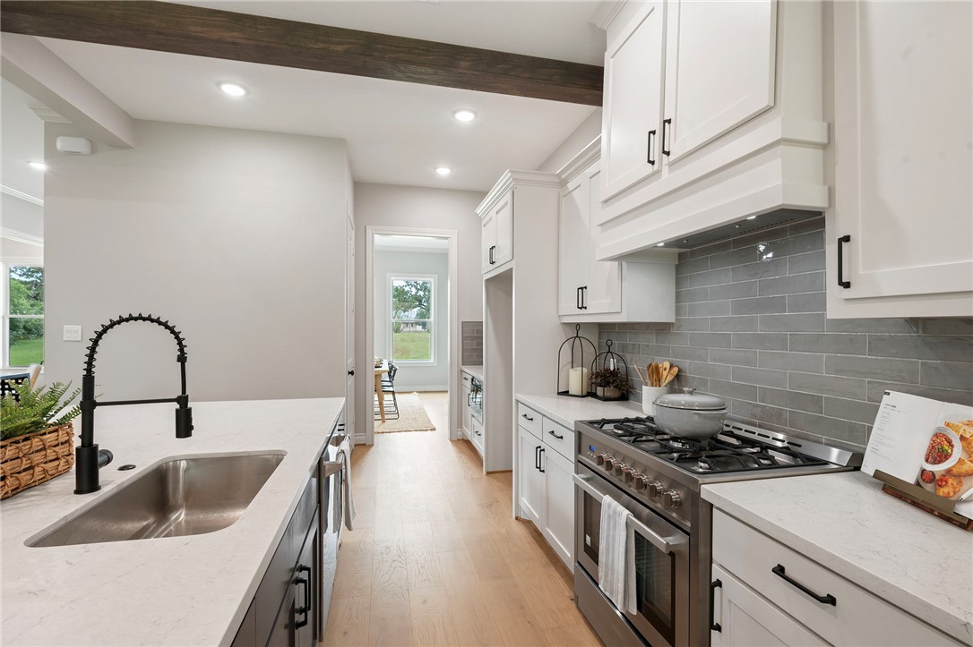 13291 Hopes Creek Road College Station, TX 77845 - Photo 11 of 45 Kitchen with range with two ovens, white cabinets, light stone countertops, backsplash, and light wood-type flooring