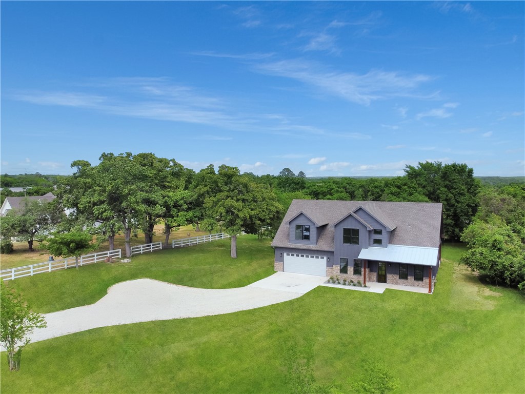 13291 Hopes Creek Road College Station, TX 77845 - Photo 4 of 45 View of front of house featuring stone siding, a front lawn, a porch, concrete driveway, and a view of rural / pastoral area