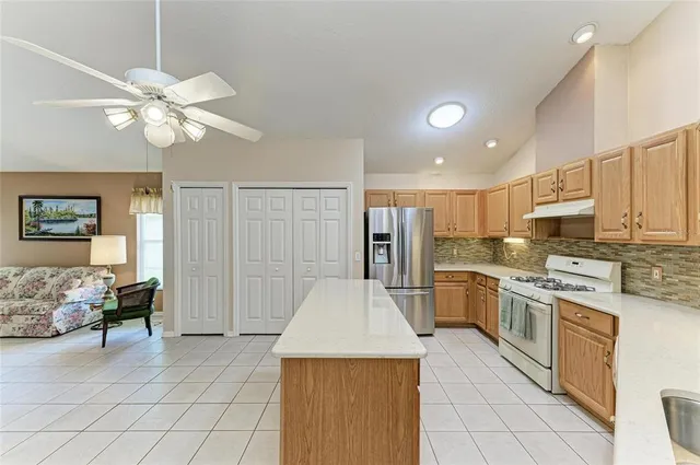 a kitchen with stainless steel appliances kitchen island granite countertop a refrigerator a stove top oven a sink and dishwasher