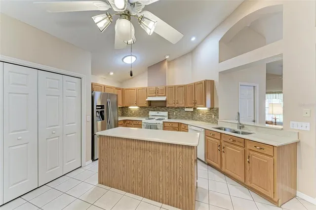 a large white kitchen with kitchen island a sink stainless steel appliances and a chandelier