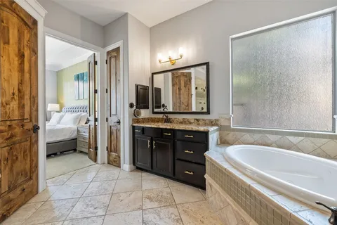 a spacious bathroom with a tub sink and mirror
