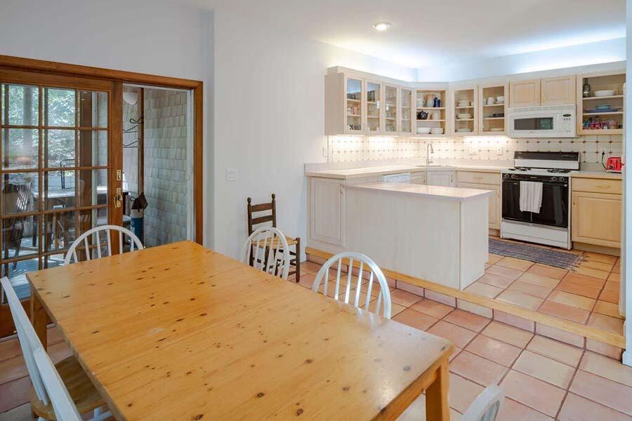 45 Old Long Pond Road Wellfleet, MA 02667 - Photo 11 of 47 a kitchen with stainless steel appliances kitchen island granite countertop a stove a sink a dining table and chairs with wooden floor