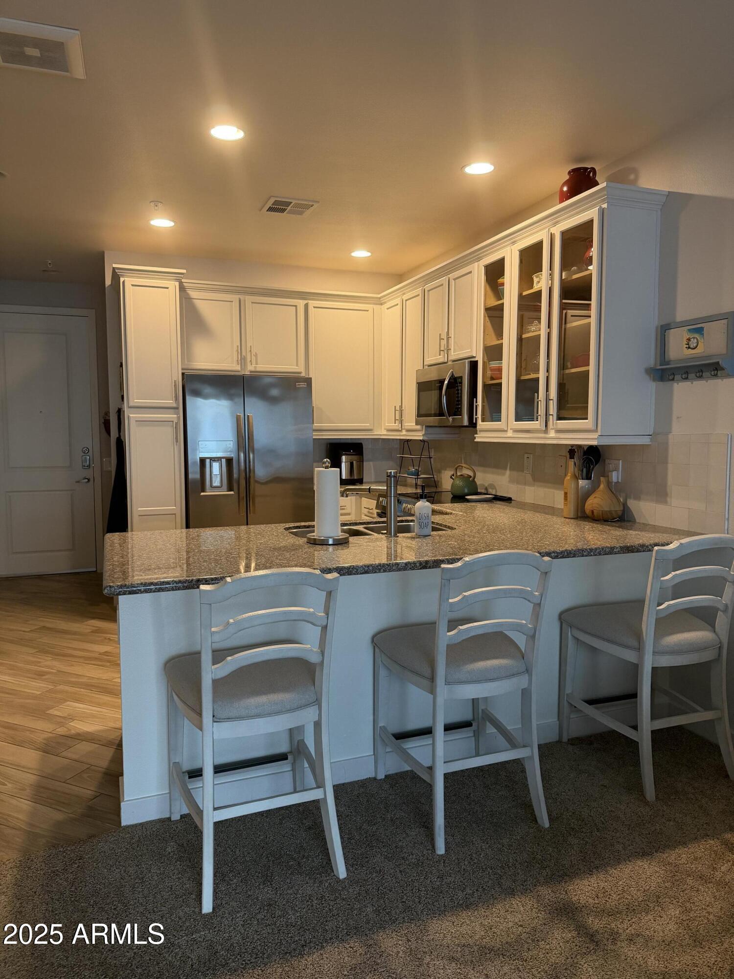2511 West Queen Creek Road, Unit 223 Chandler, AZ 85248 - Photo 22 of 29 a kitchen with a table chairs refrigerator and cabinets