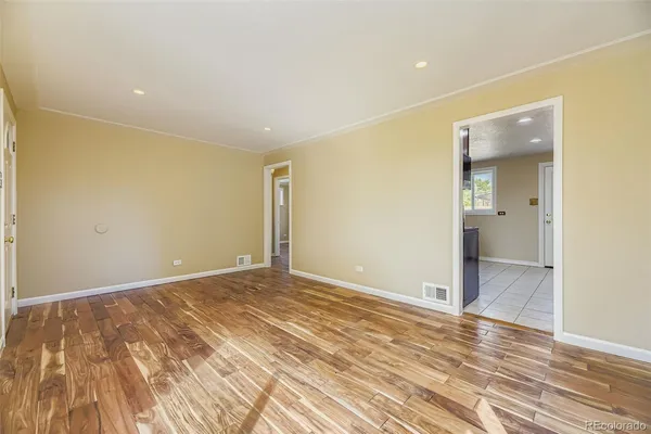 a view of an empty room with wooden floor and a bathroom