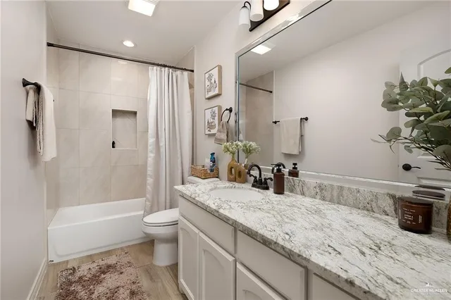 a bathroom with a granite countertop sink a toilet a mirror a bathtub and shower
