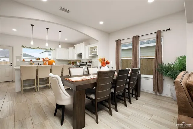 a dining room with stainless steel appliances a table chairs and a kitchen view