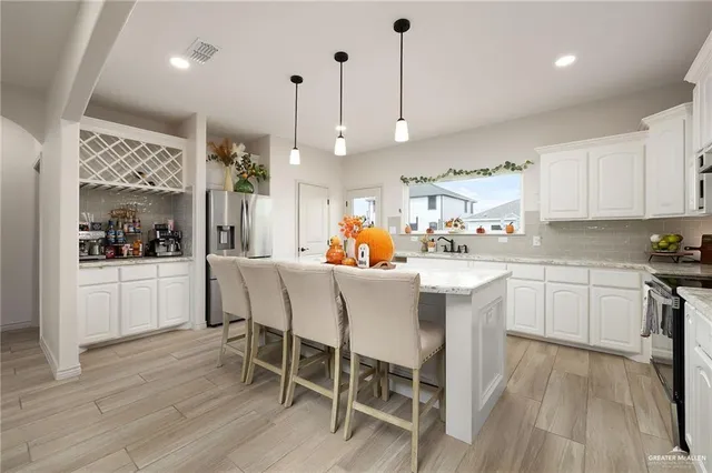 a kitchen with stainless steel appliances a dining table chairs stove refrigerator and cabinets