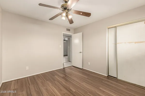 an empty room with wooden floor fan and windows