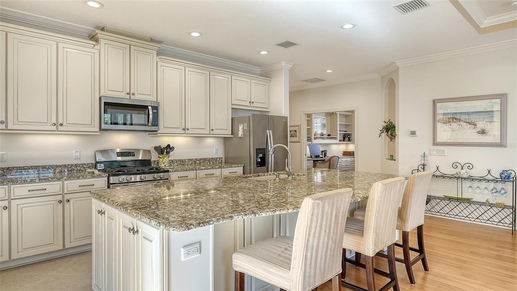 12759 Del Corso Loop Bradenton, FL 34211 - Photo 19 of 74 a kitchen with stainless steel appliances granite countertop a stove a sink a microwave a dining table and chairs