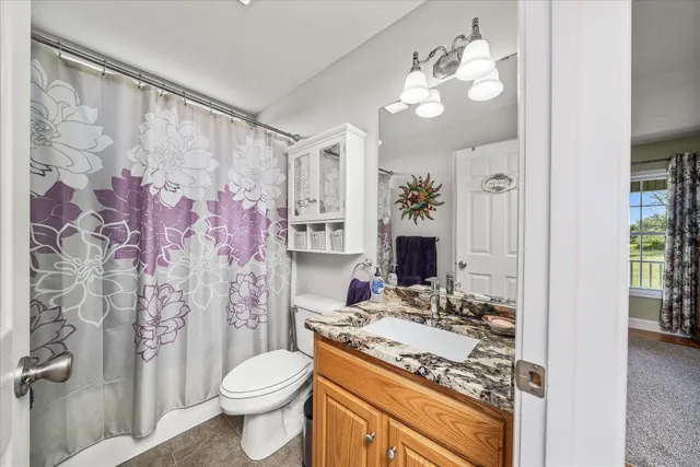 a bathroom with a granite countertop sink mirror vanity and toilet