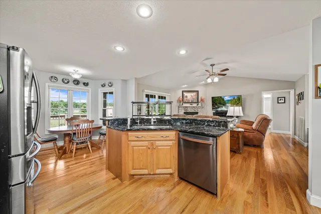 a kitchen with stainless steel appliances granite countertop a stove top oven a dining table and chairs with wooden floor