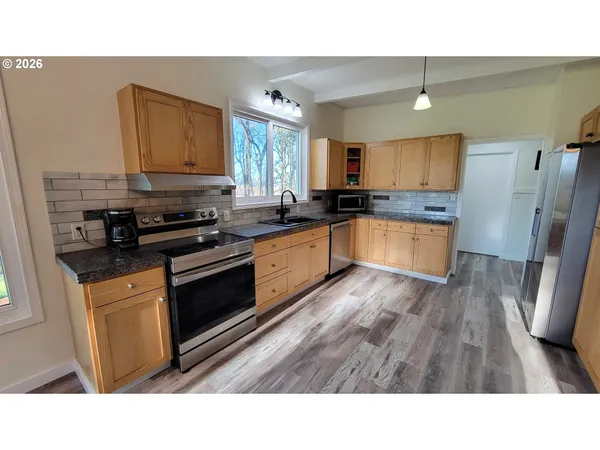 a kitchen with stainless steel appliances a refrigerator and wooden floor
