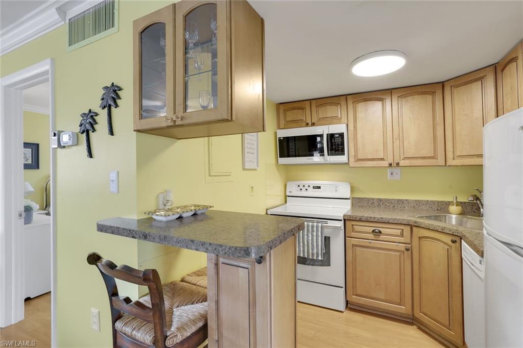780 10th Avenue South, Unit 22 Naples, FL 34102 - Photo 9 of 17 a kitchen with stainless steel appliances granite countertop a stove a sink and a microwave
