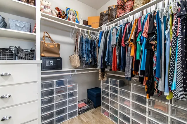 a view of walk in closet with clothes and shoes