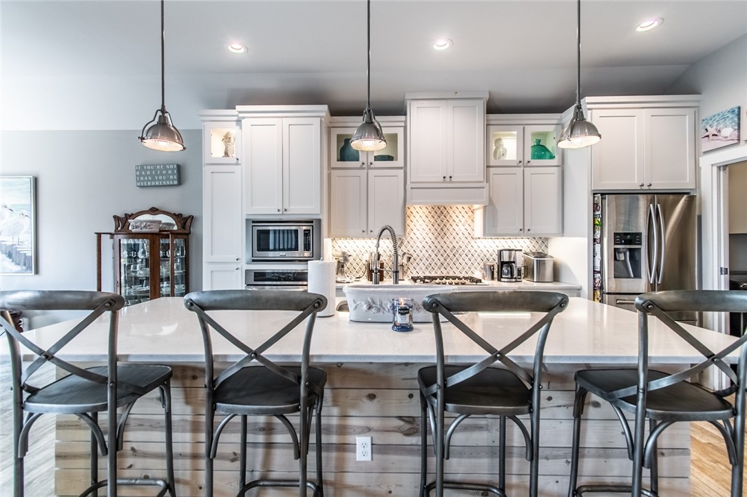 15422 Dyna Street Corpus Christi, TX 78418 - Photo 32 of 40 a kitchen with stainless steel appliances kitchen island granite countertop a dining table chairs and a refrigerator