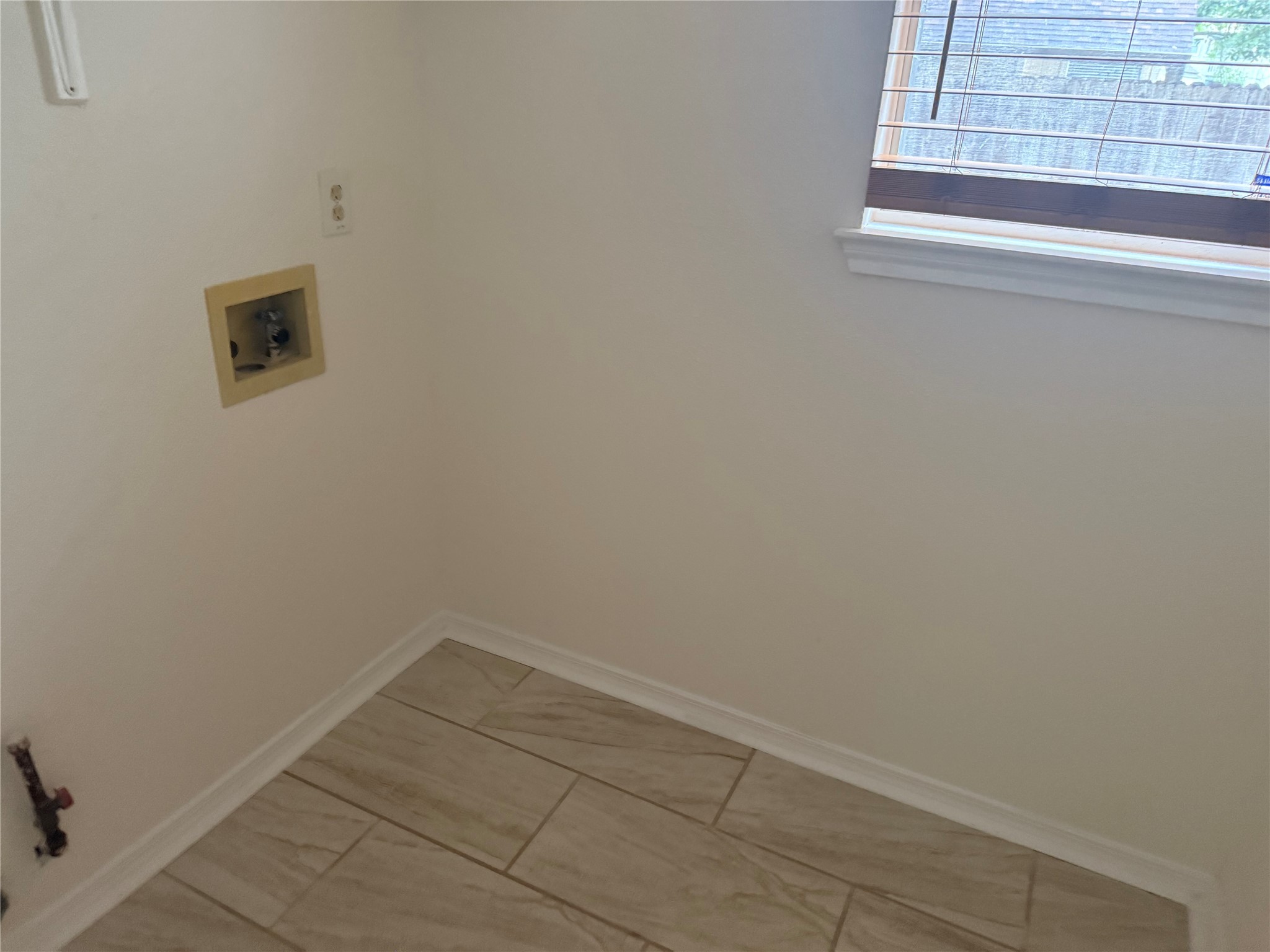 16910 Isle Of Man Road Pflugerville, TX 78660 - Photo 11 of 13 Dedicated laundry area featuring a window with horizontal blinds, neutral wall paint, and light-toned tile flooring