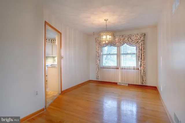 an empty room with wooden floor mirror and windows