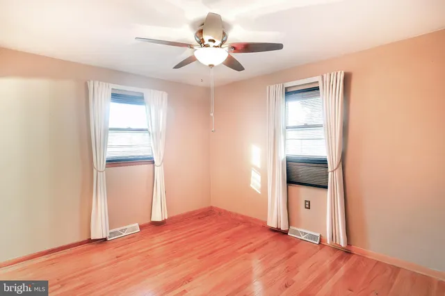 a view of a room with wooden floor and a ceiling fan