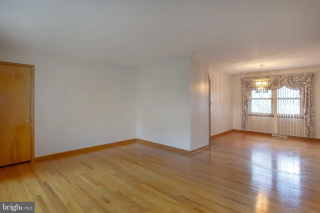a view of an empty room with wooden floor and window