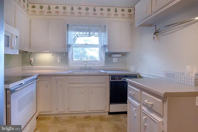 a kitchen with cabinets appliances a sink and a window