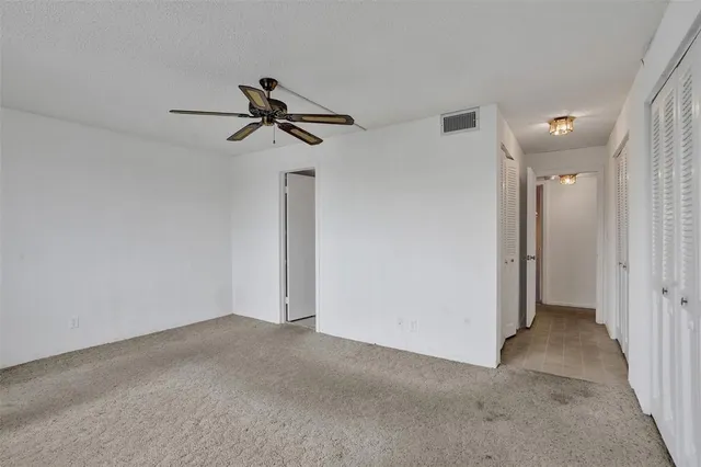 a view of empty room with wooden floor and ceiling fan