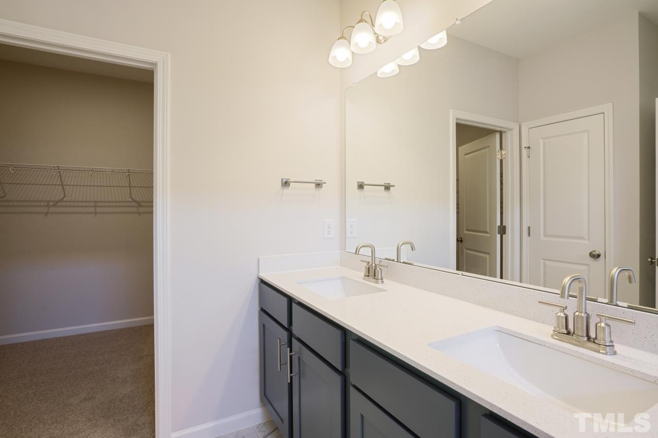 393 Madden Rose Loop Garner, NC 27529 - Photo 22 of 31 a bathroom with a sink a light fixture and a mirror