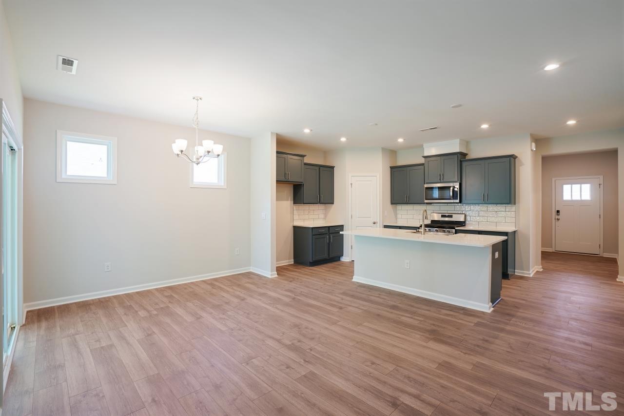 393 Madden Rose Loop Garner, NC 27529 - Photo 6 of 31 a view of kitchen with kitchen island granite countertop wooden floor stainless steel appliances and cabinets