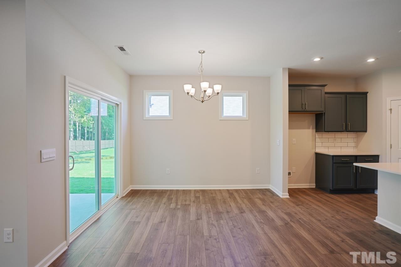 393 Madden Rose Loop Garner, NC 27529 - Photo 7 of 31 a view of an empty room with a window and wooden floor