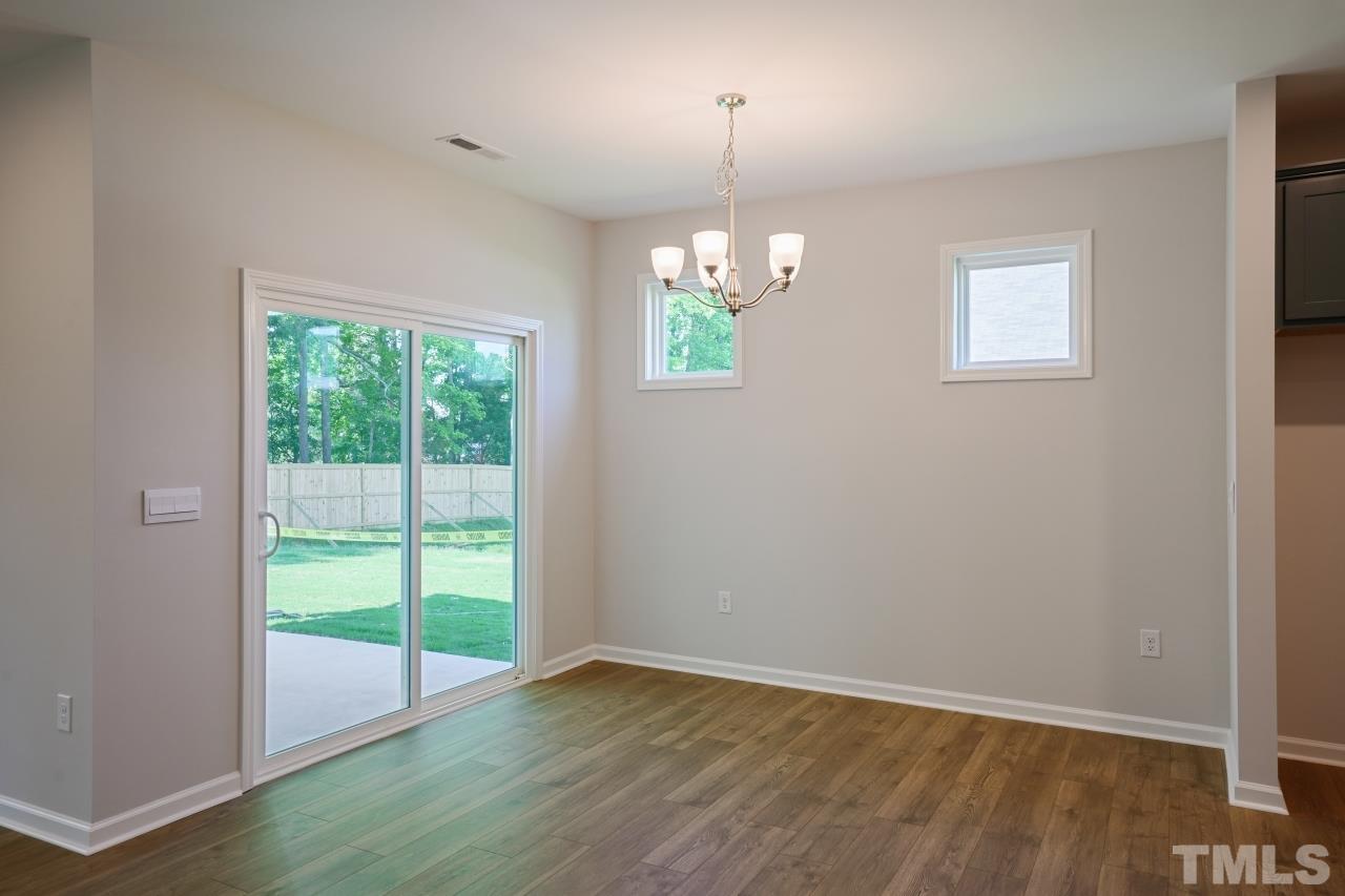393 Madden Rose Loop Garner, NC 27529 - Photo 10 of 31 an empty room with wooden floor chandelier and windows