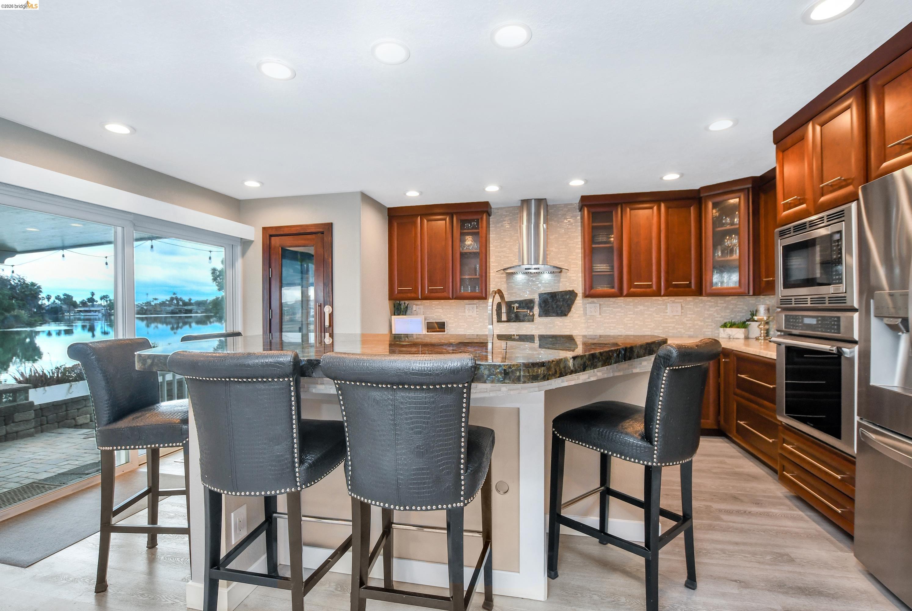 1432 Willow Lake Road Discovery Bay, CA 94505 - Photo 11 of 40 Gourmet kitchen featuring rich wood cabinetry, stainless steel appliances, a multi-level island with seating, recessed lighting, and a full backsplash