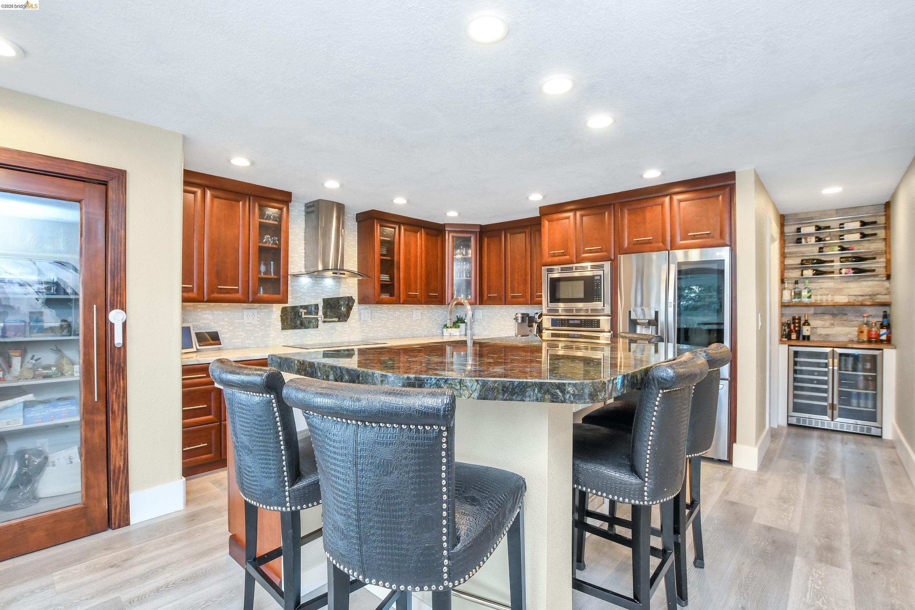1432 Willow Lake Road Discovery Bay, CA 94505 - Photo 12 of 40 Gourmet kitchen featuring rich wood cabinetry, stainless steel appliances, a large center island with a dark stone countertop, recessed lighting, and wood-finish flooring
