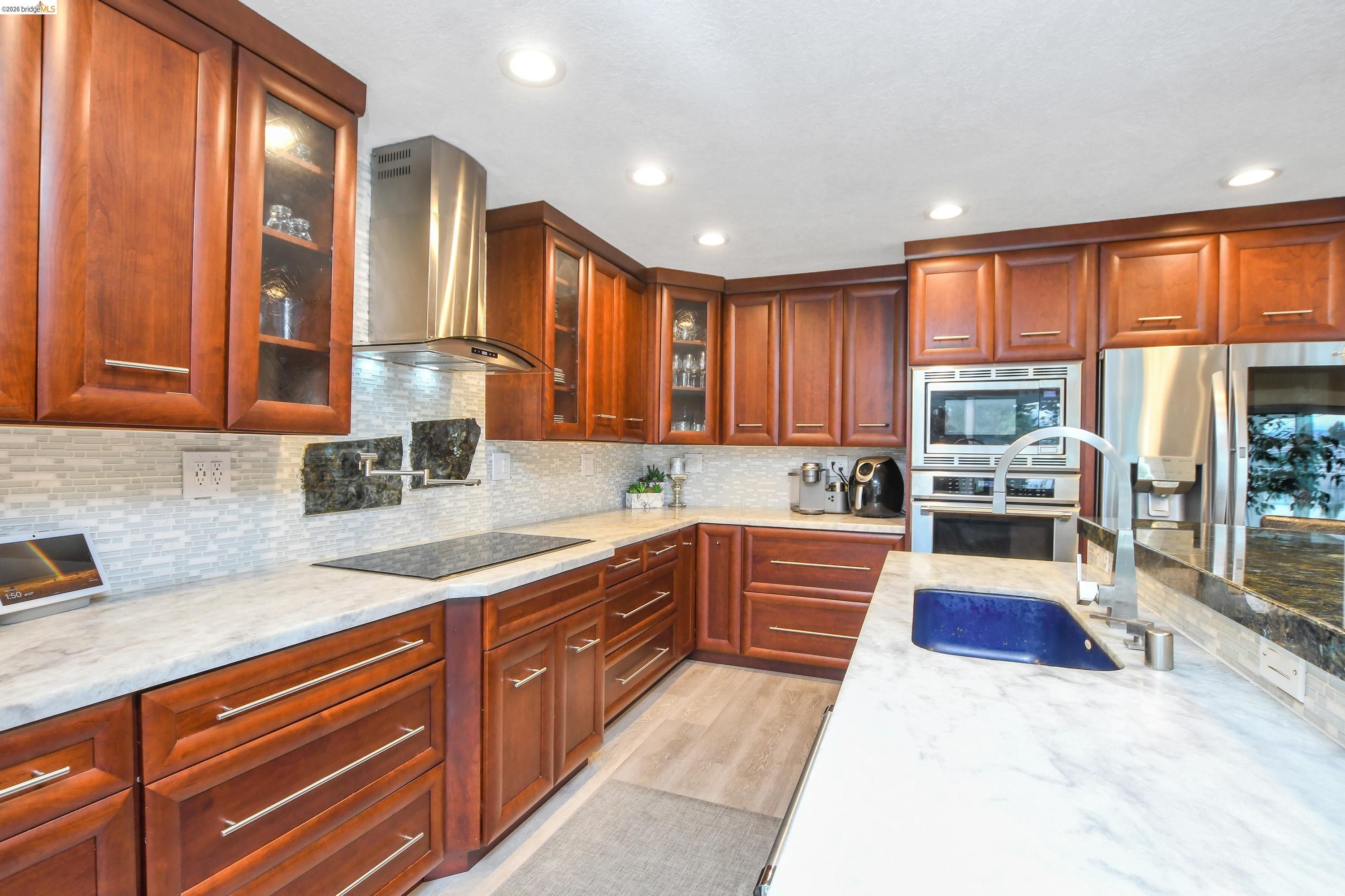 1432 Willow Lake Road Discovery Bay, CA 94505 - Photo 14 of 40 Corner kitchen featuring warm wood cabinetry, light-toned countertops, a tile backsplash, stainless steel appliances, and recessed lighting