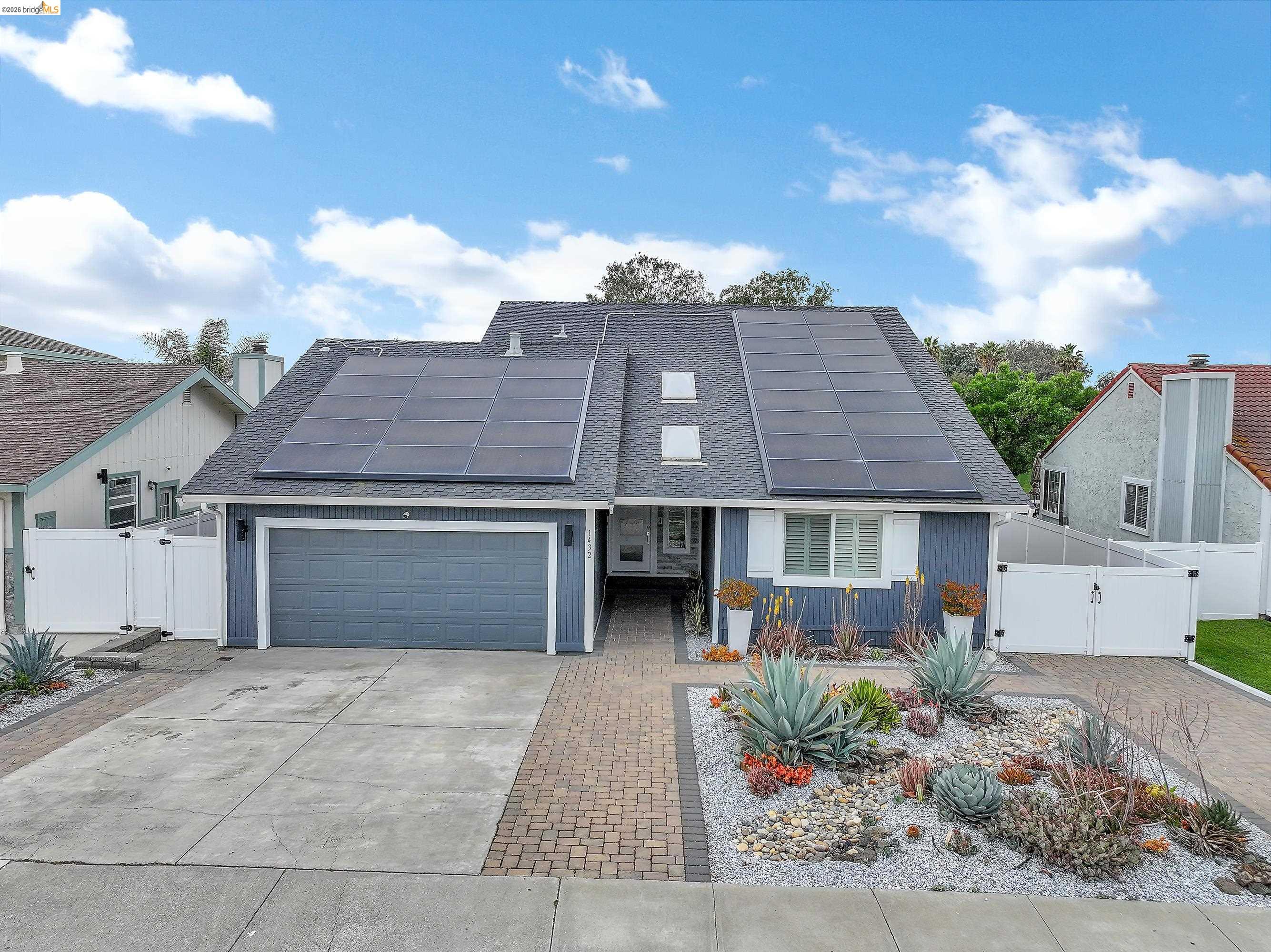 1432 Willow Lake Road Discovery Bay, CA 94505 - Photo 2 of 40 Exterior featuring a blue horizontal siding facade, an attached two-car garage, and a grey shingle roof with solar panels