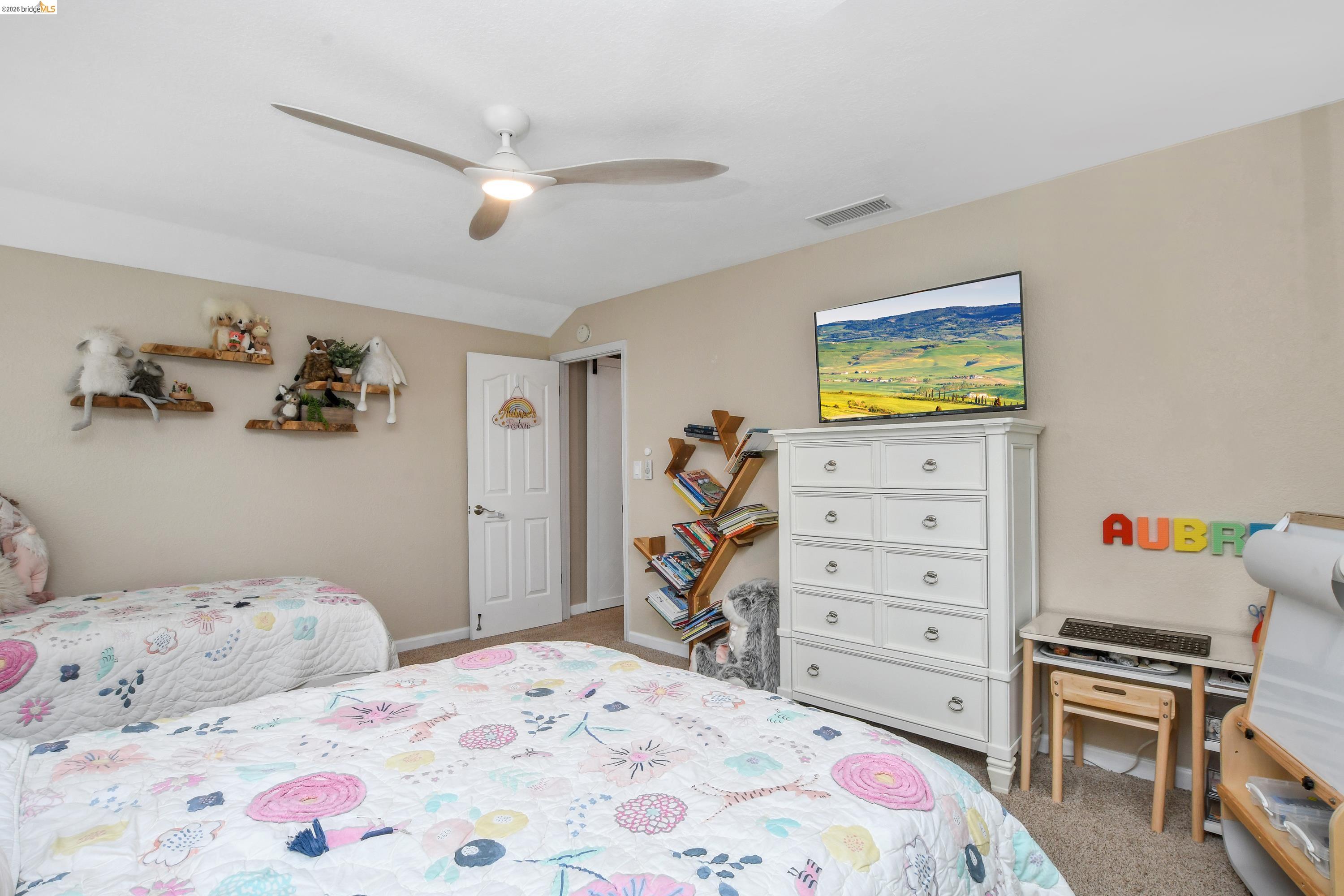 1432 Willow Lake Road Discovery Bay, CA 94505 - Photo 26 of 40 Carpeted room featuring a ceiling fan with integrated lighting, a white six-drawer dresser, a built-in wood-finish book display, a white paneled door, and neutral wall paint