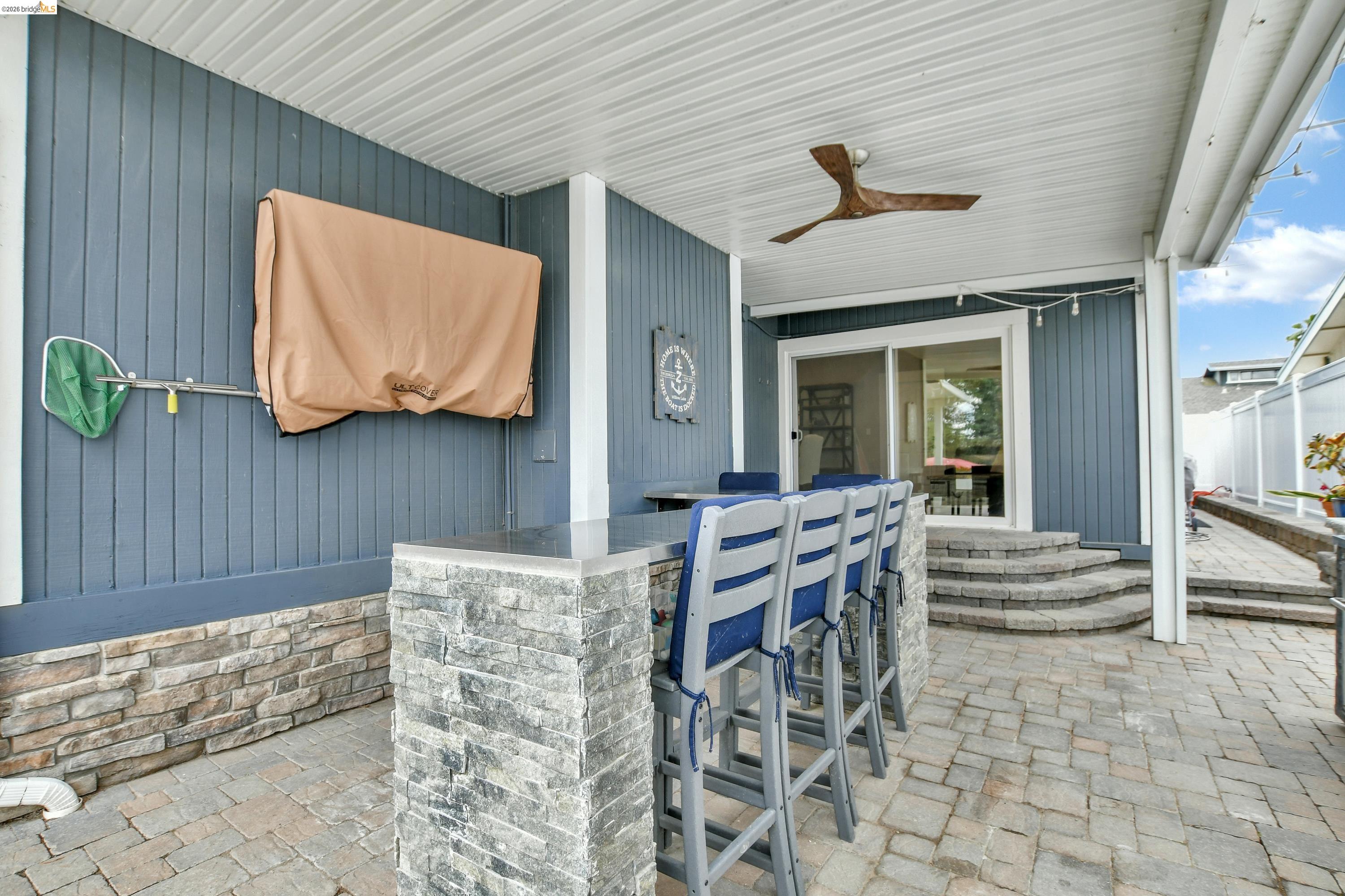 1432 Willow Lake Road Discovery Bay, CA 94505 - Photo 36 of 40 Covered outdoor patio featuring a stone-clad bar with seating, ceiling fan, and sliding glass door access to the interior