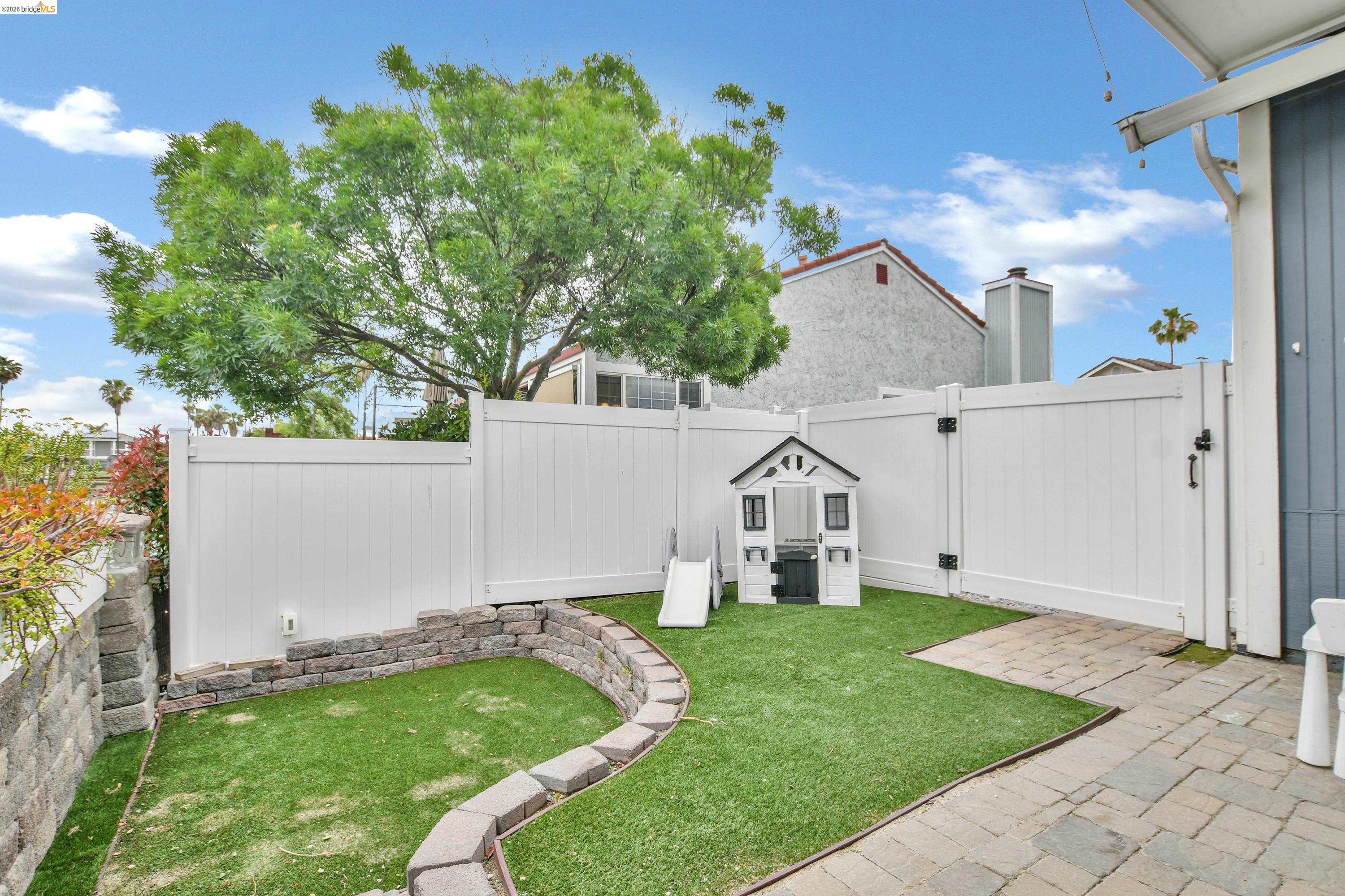 1432 Willow Lake Road Discovery Bay, CA 94505 - Photo 38 of 40 Enclosed backyard featuring artificial turf, a white vinyl fence, and a stone retaining wall