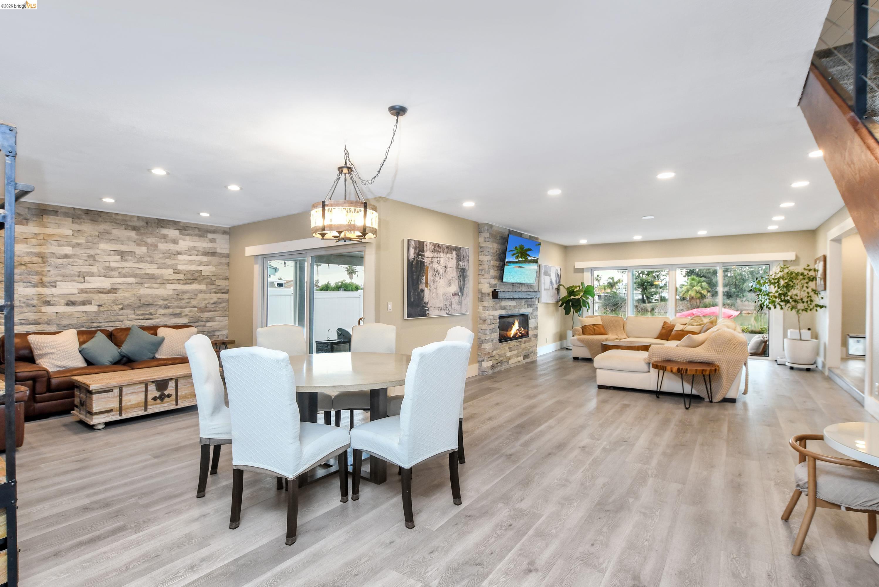 1432 Willow Lake Road Discovery Bay, CA 94505 - Photo 6 of 40 Open-concept interior featuring wood-finish flooring, a stone-clad accent wall, a built-in fireplace with stone surround, recessed lighting, and sliding glass doors to an outdoor area